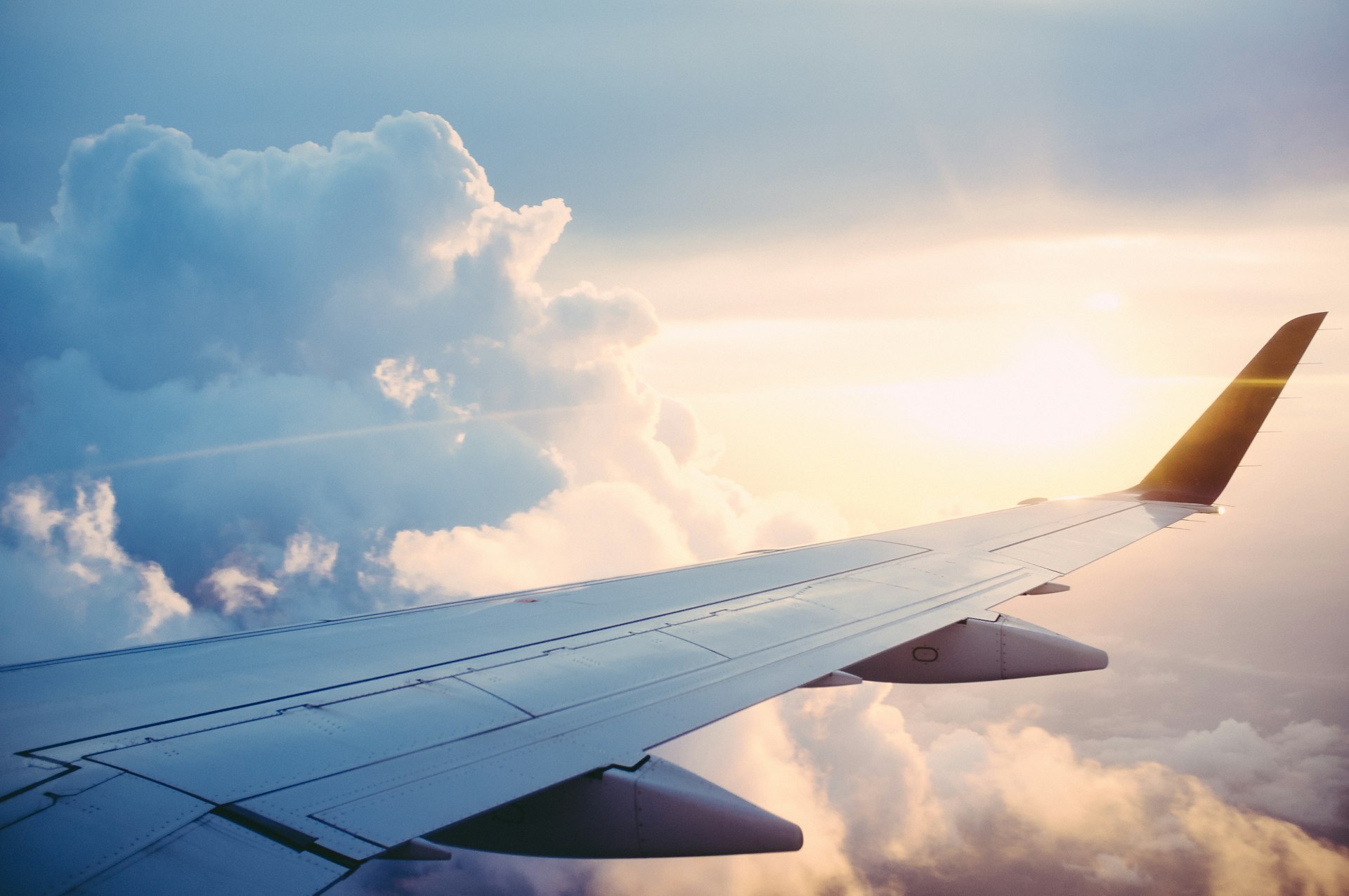 Airplane soaring above clouds at sunset — luxury travel with Roz Travels